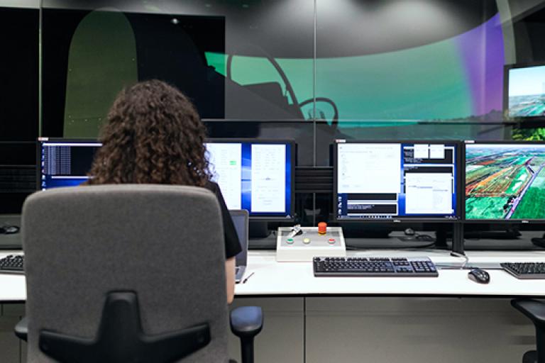 Woman sitting in a chair looking at multiple monitors