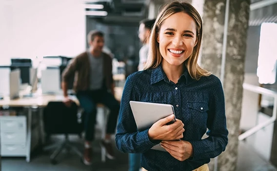 Woman smiling while holding a tablet standing in an office