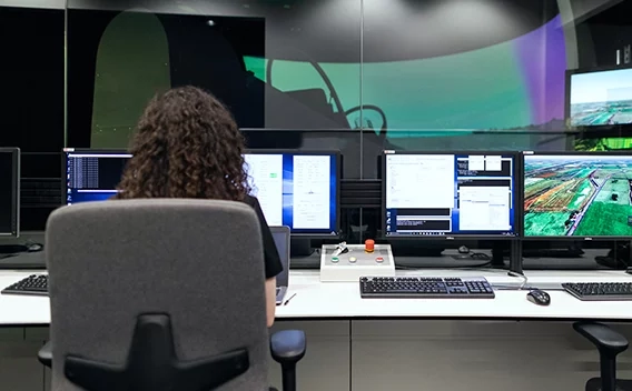 woman sitting in office chair looking at several monitors